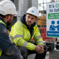Two construction workers in PPE having a supportive conversation during a break, highlighting mental health awareness and wellbeing on a UK construction site.
